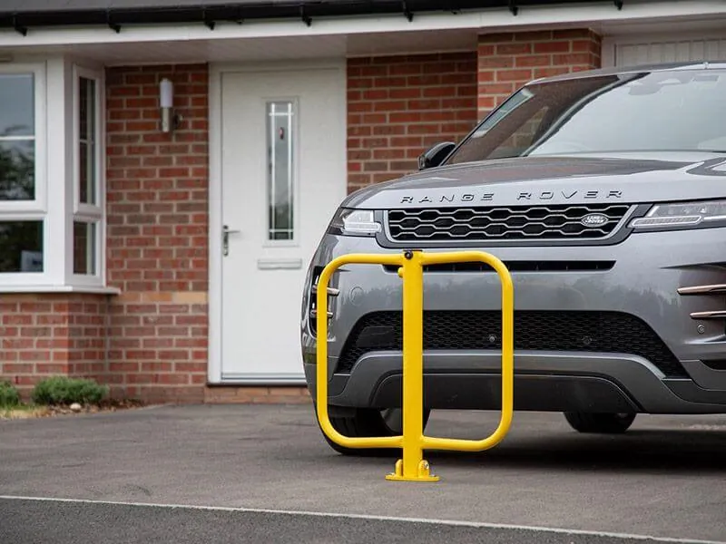 A yellow fold-down parking post in front of an SUV on a driveway